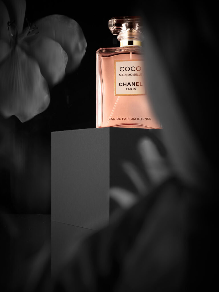 Perfume Coco Chanel Mademoiselle sobre fondo floral negro