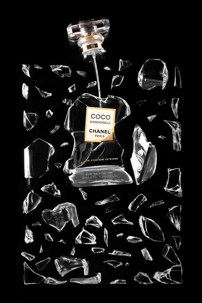 Perfume Coco Chanel Mademoiselle roto y ordenado sobre fondo negro